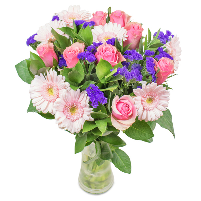 An eye-catching floral centerpiece designed for Clapham homes, elegantly displayed in a clear glass vase against a crisp white background. At its heart are seven to nine medium pink roses, many with petals gently furled, some unfurling with romantic promise-each bloom echoing the charm of Clapham's leafy avenues. Complementing them are five to seven pale pink Gerbera daisies, their large, soft heads and notably light centers imparting a gentle, approachable feel. Throughout, vivid purple statice clusters provide energy, their texture and depth reminiscent of wildflowers found near Battersea Rise. Generous deep green foliage frames the arrangement, lending vibrancy and grounding the bouquet with a touch of the parks that define the area. The stems are visible through the glass, suggesting freshness and authenticity, ready to grace a dinner table in Northcote Road or brighten an office reception. Perfect for birthdays, anniversaries, Mother's Day, or heartfelt thanks, this Clapham-inspired bouquet delivers joy, affection, and a flourish of local floral artistry.